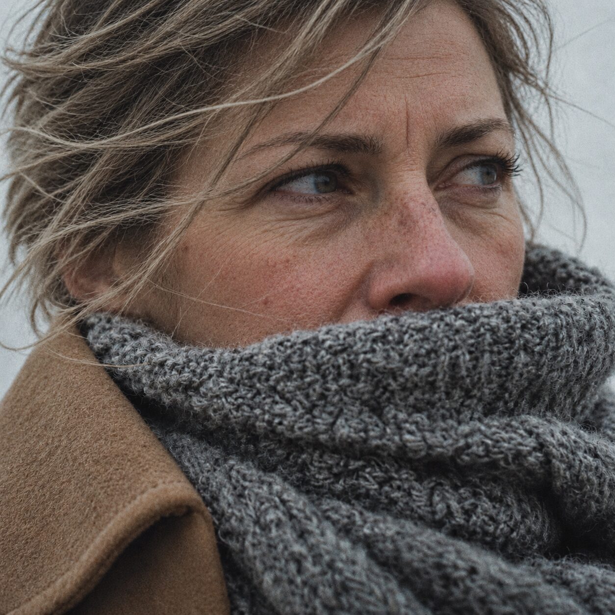 Frau mit Strickschal im Winterwind